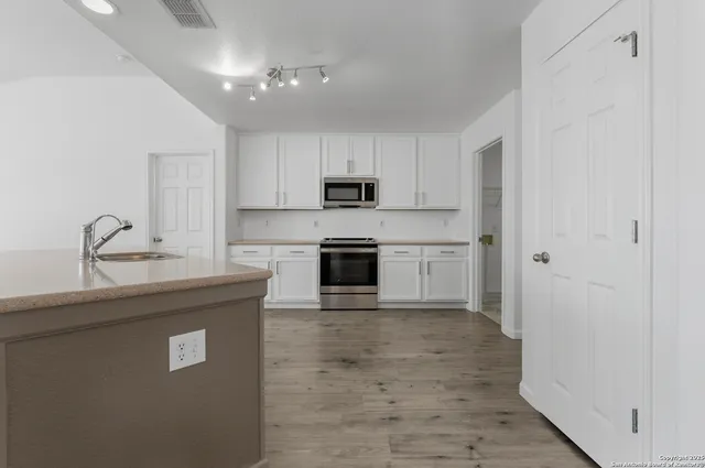 a kitchen with granite countertop a refrigerator oven a sink and dishwasher