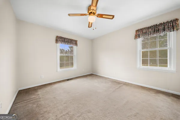 an empty room with windows and fan