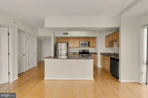a large white kitchen with stainless steel appliances a refrigerator a stove a microwave and cabinets