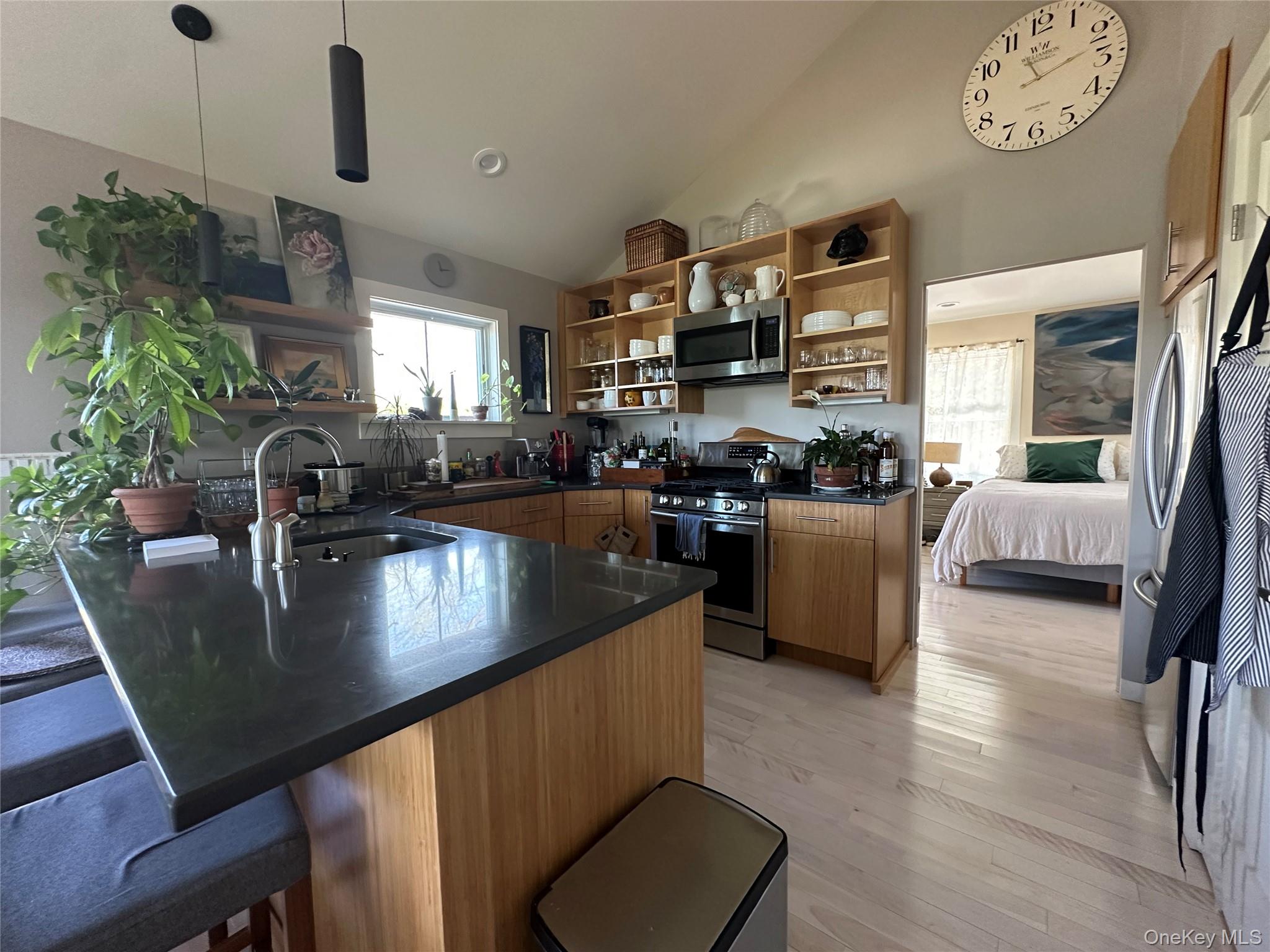 1854 North Bayview Road Southold, NY 11971 - Photo 16 of 20 Kitchen featuring open shelves, appliances with stainless steel finishes, dark countertops, a peninsula, and a kitchen bar