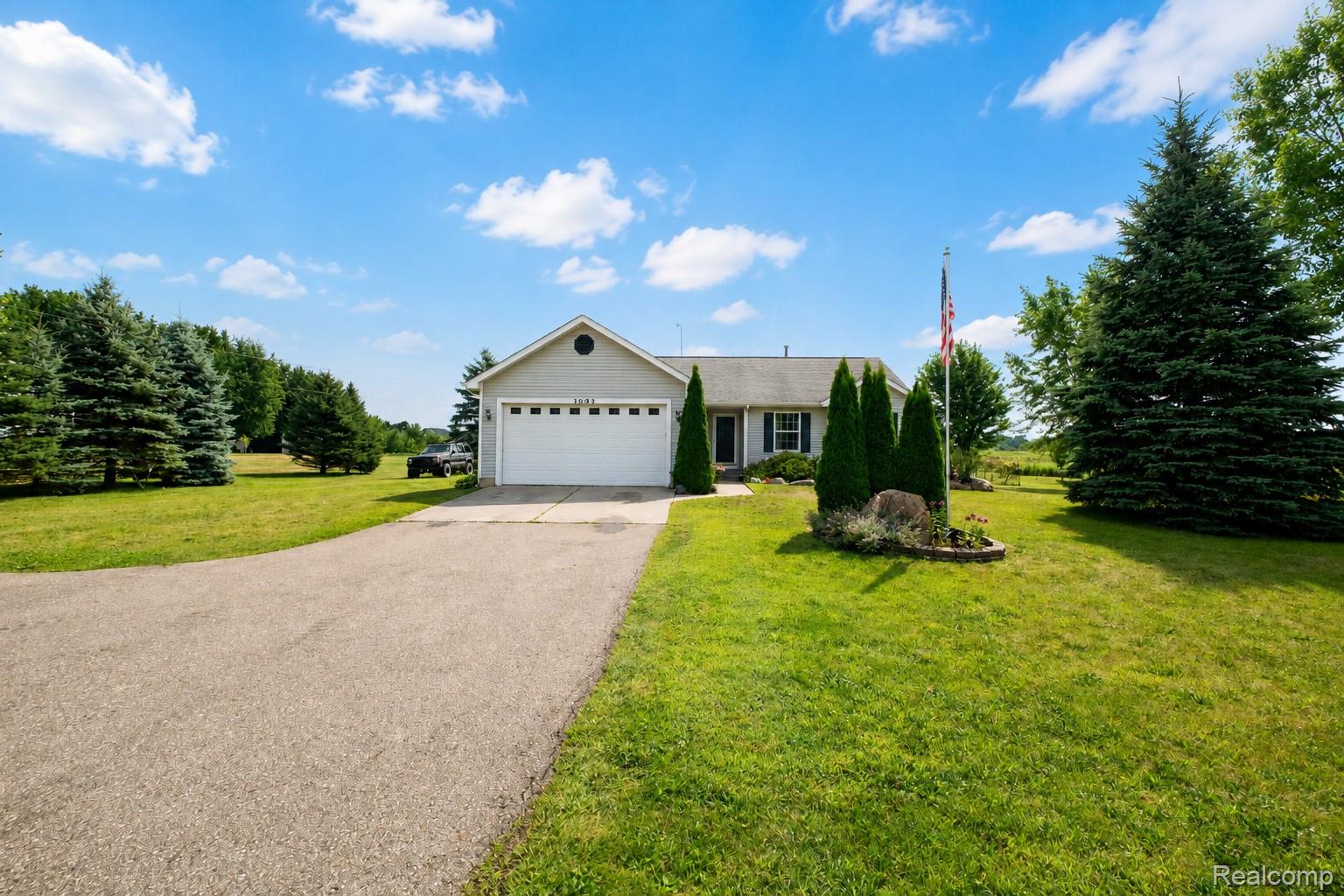 Single-story residence featuring a two-car garage, paved driveway, and expansive lawn