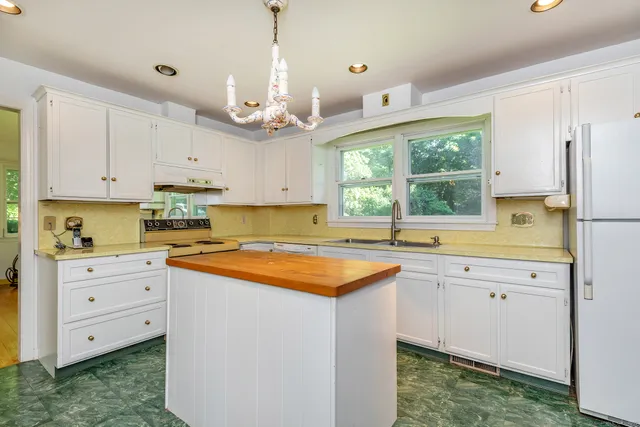 a kitchen with stainless steel appliances granite countertop a sink a stove a refrigerator and white cabinets with wooden floor