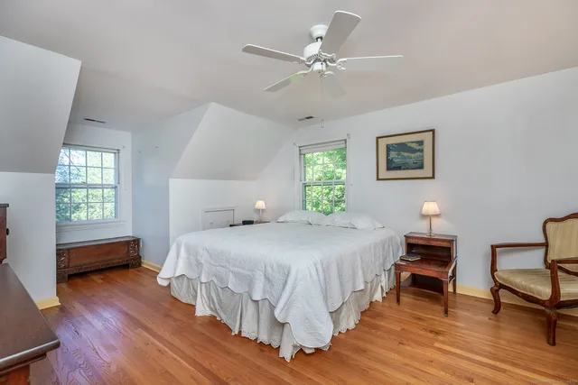 a bedroom with a bed a dresser and wooden floor