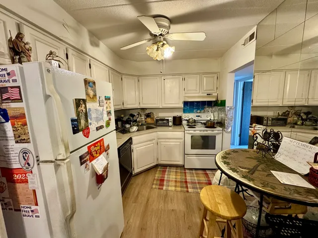 a kitchen with granite countertop stainless steel appliances a sink a stove a refrigerator cabinets and dining table