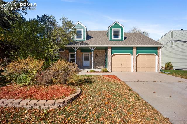 103 Saddlemountain Road Colorado Springs, CO 80919 - Photo 19 of 30 Cape cod-style house featuring covered porch, brick siding, concrete driveway, a shingled roof, and a garage