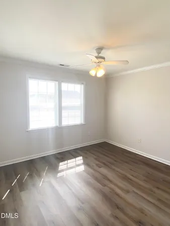 an empty room with wooden floor fan and windows