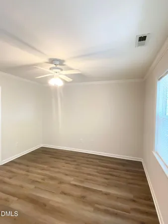 a view of an empty room with wooden floor and a window