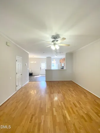 a view of a big room with wooden floor and chandelier fan