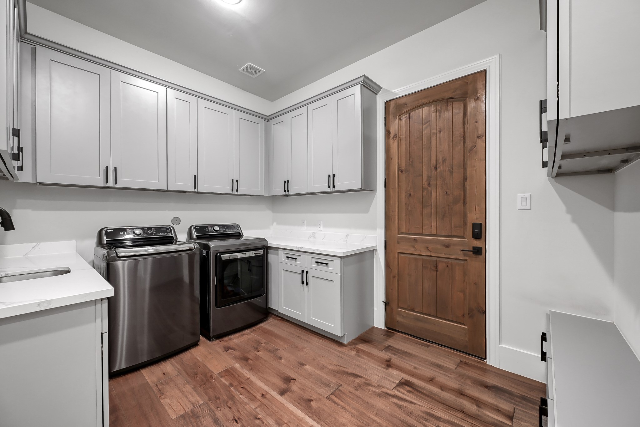 15937 Stagecoach Road Stagecoach, TX 77355 - Photo 30 of 50 This photo showcases a massive laundry room with ample cabinetry, a Knotty Alder wooden door. Offering a functional and stylish space for household tasks.