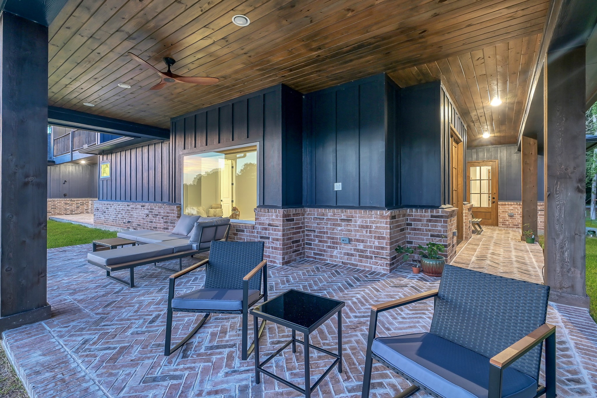 15937 Stagecoach Road Stagecoach, TX 77355 - Photo 38 of 50 Covered patio with stylish brick flooring and dark wood ceiling accents, a ceiling fan, and ambient lighting, ideal for outdoor relaxation or entertaining.