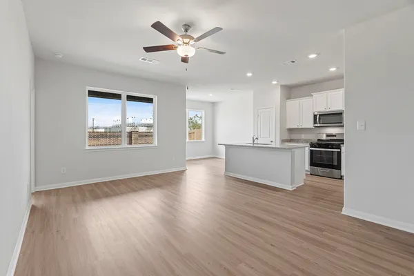 a view of an empty room with kitchen and window