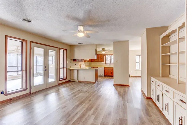 a large white kitchen with wooden floor and a large window