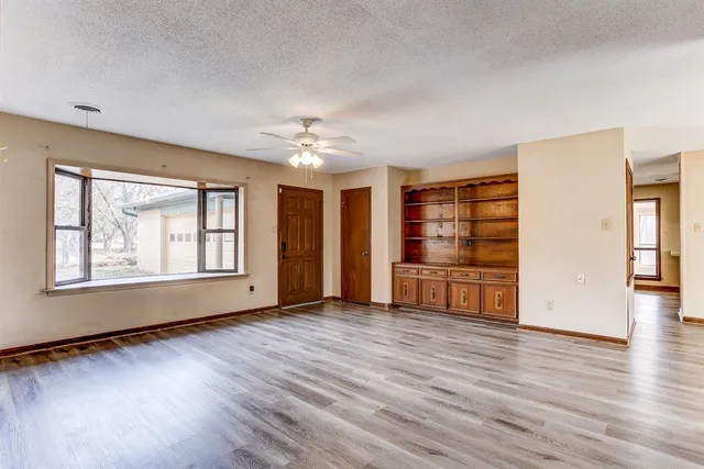 a view of an empty room with a window and wooden floor