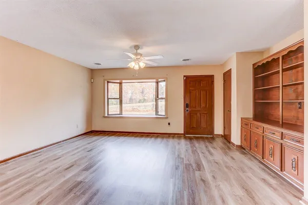 an empty room with wooden floor closet and windows