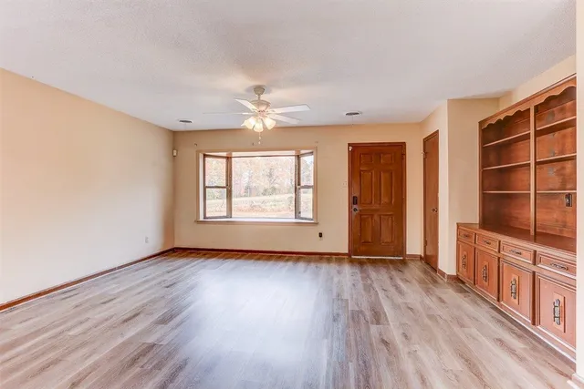 an empty room with wooden floor closet and windows