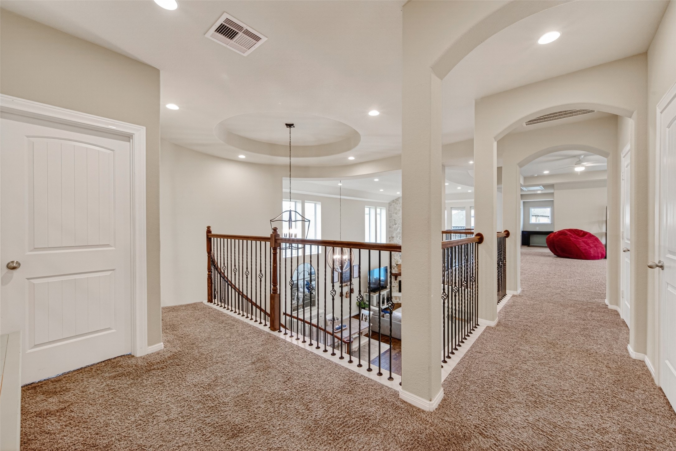 25611 Ellis Ridge Court Katy, TX 77494 - Photo 22 of 49 This photo showcases a spacious, carpeted upper landing with elegant railings overlooking a living area. The space is well-lit with recessed lighting and features multiple doorways leading to other rooms, providing a cozy and open feel.