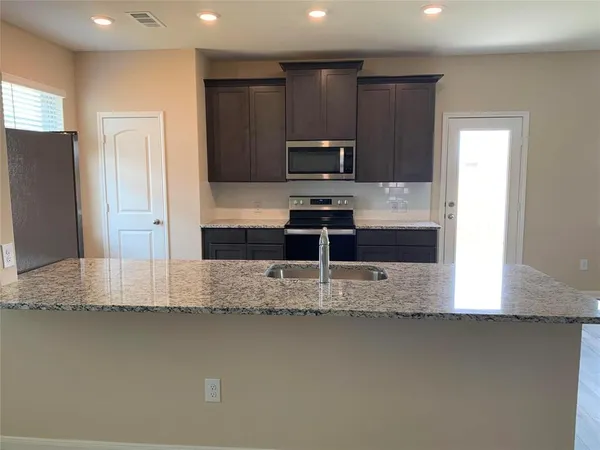 a kitchen with kitchen island granite countertop a sink and a stove top oven