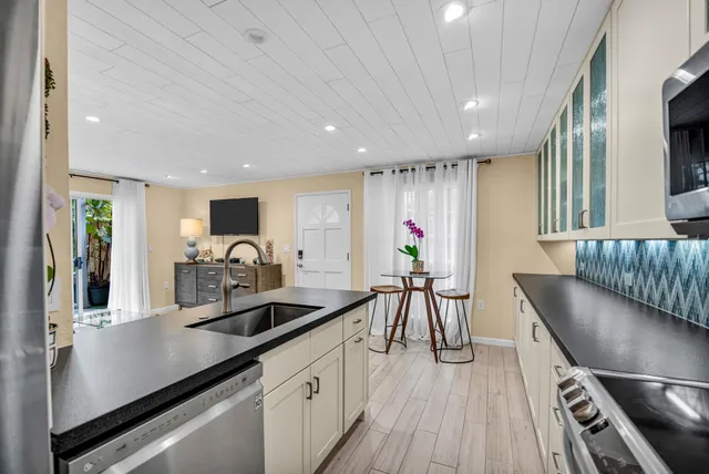 a kitchen with stainless steel appliances kitchen island granite countertop a table chairs in it and wooden floors