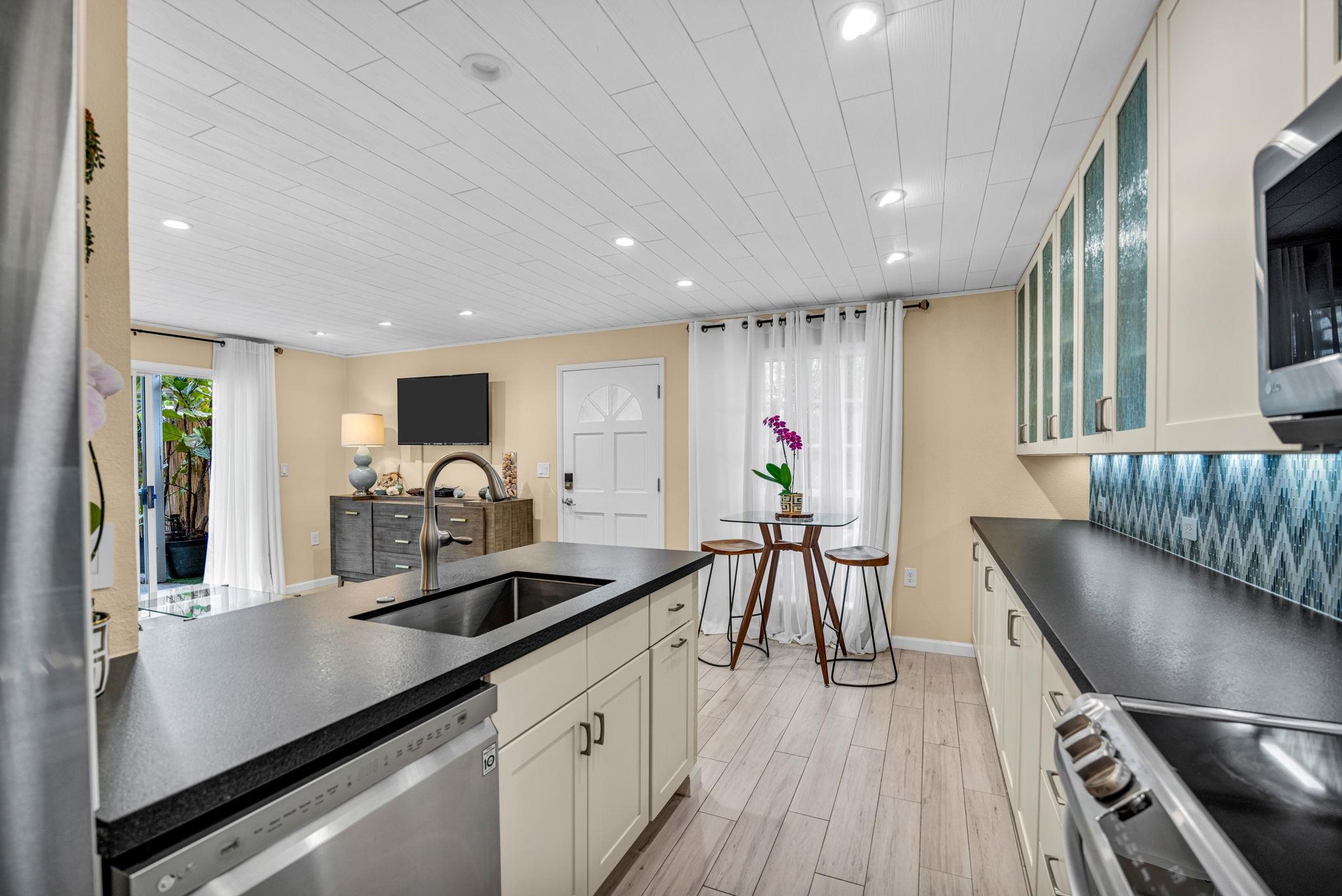 160 Keonekai Road, Unit 8103 Kihei, HI 96753 - Photo 11 of 47 a kitchen with stainless steel appliances kitchen island granite countertop a table chairs in it and wooden floors