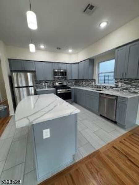 38 Blum Street Newark, NJ 07103 - Photo 4 of 15 a kitchen with stainless steel appliances granite countertop wooden cabinets a sink a stove a refrigerator and island
