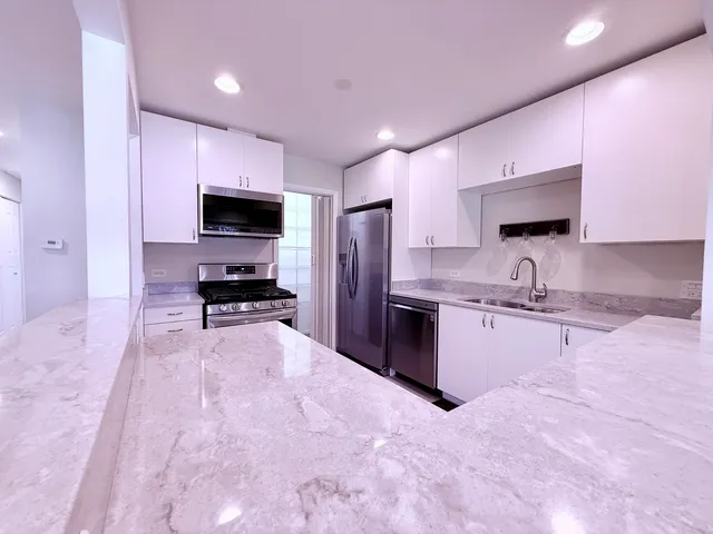 a large kitchen with granite countertop a sink stainless steel appliances and cabinets