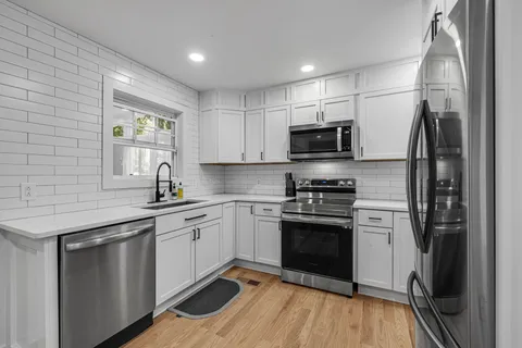 a kitchen with a refrigerator sink and white cabinets
