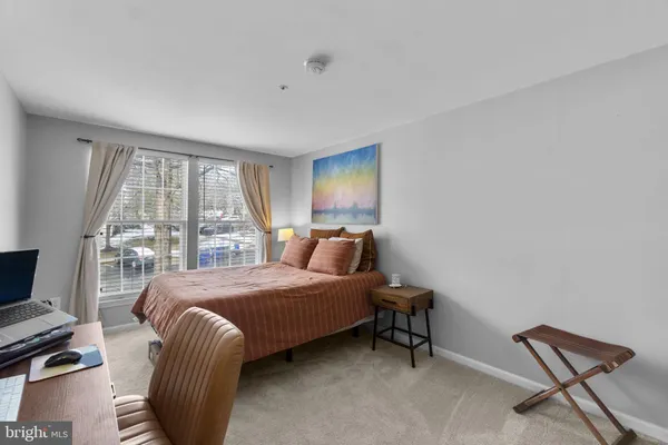 a bedroom with a bed a chair and potted plant on the dresser