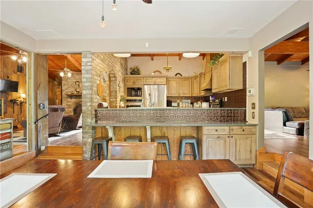 a living room with stainless steel appliances granite countertop table chairs and a large window