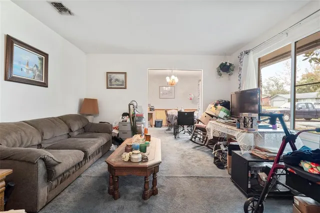 a living room with furniture two large window and a flat screen tv