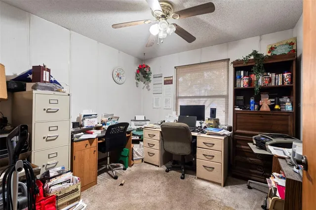 a view of a workspace with furniture and a ceiling fan