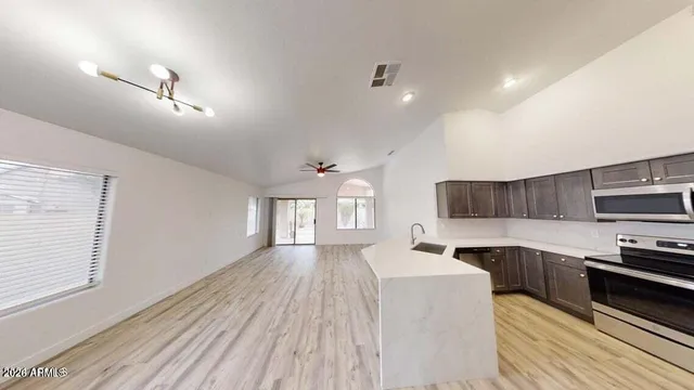 a large kitchen with cabinets appliances wooden floor and a window