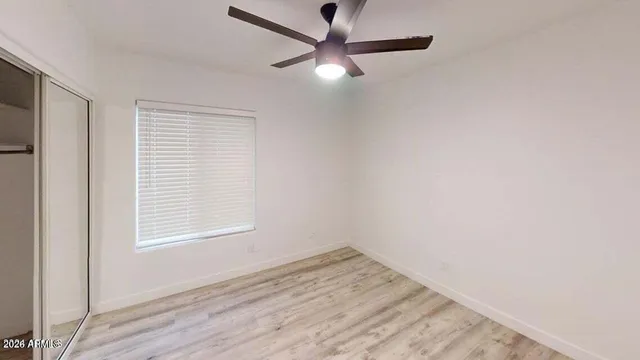 an empty room with a window and a ceiling fan