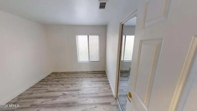an empty room with wooden floor and windows