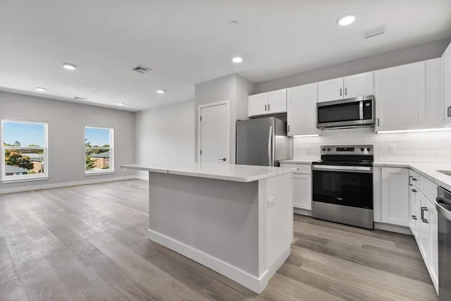 a kitchen with granite countertop a refrigerator and a stove top oven