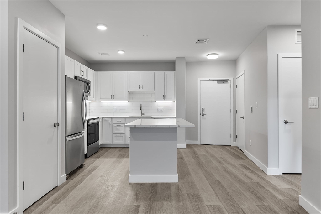 59 Mill Street, Unit 203 Woburn, MA 01801 - Photo 2 of 19 a kitchen with white cabinets and stainless steel appliances