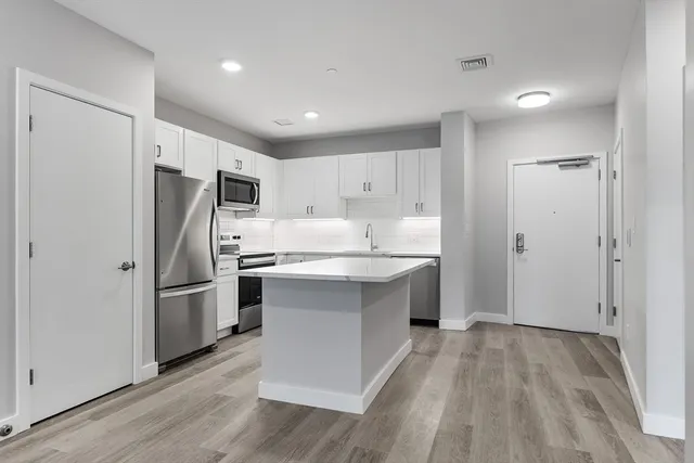 a kitchen with a refrigerator a sink and dishwasher with wooden floor
