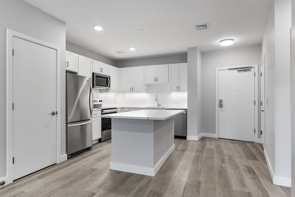 59 Mill Street, Unit 203 Woburn, MA 01801 - Photo 4 of 19 a kitchen with a refrigerator a sink and dishwasher with wooden floor