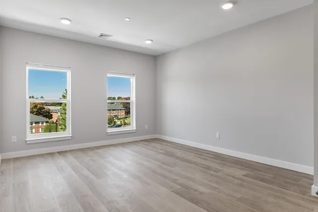 an empty room with wooden floor and window