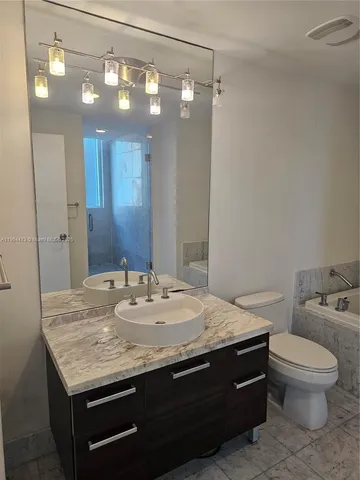 a bathroom with a granite countertop sink a toilet and a mirror