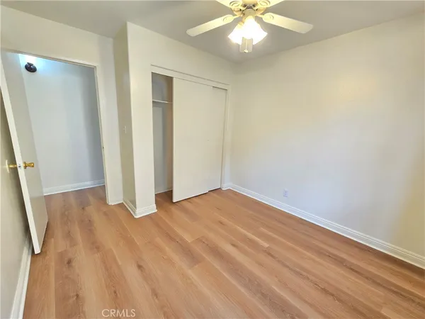 an empty room with wooden floor and fan
