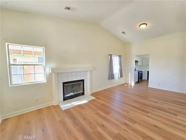 an empty room with wooden floor fireplace and windows