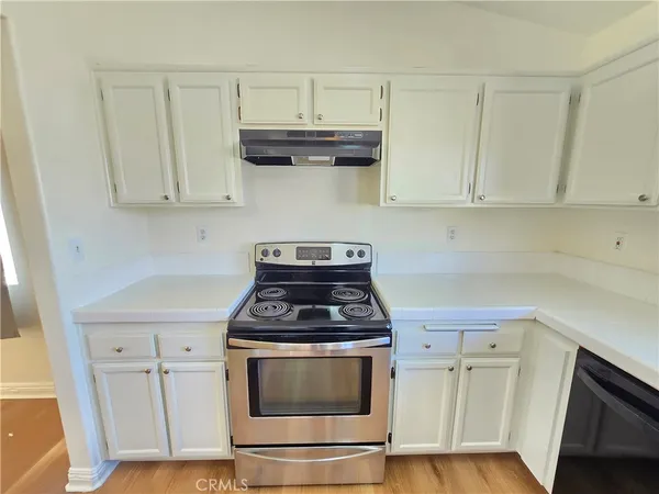 a kitchen with granite countertop white cabinets and a stove with wooden floor