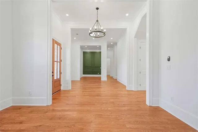a view of an empty room with wooden floor and a kitchen
