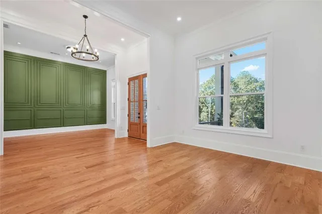 an empty room with wooden floor cabinet and windows