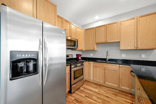 a kitchen with stainless steel appliances granite countertop a refrigerator a stove and a sink with cabinets