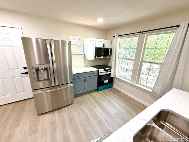 a kitchen with stainless steel appliances granite countertop a refrigerator a stove a sink dishwasher a microwave oven with white cabinets and wooden floor