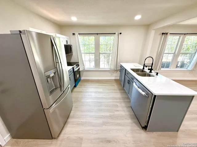 a kitchen with stainless steel appliances granite countertop a refrigerator a sink a stove a washer dryer and a refrigerator