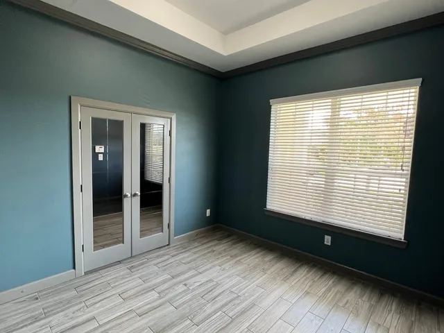 a view of an empty room with wooden floor and a window
