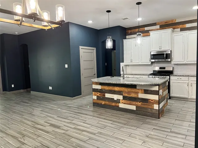 a kitchen with stainless steel appliances kitchen island granite countertop a stove a sink and a refrigerator