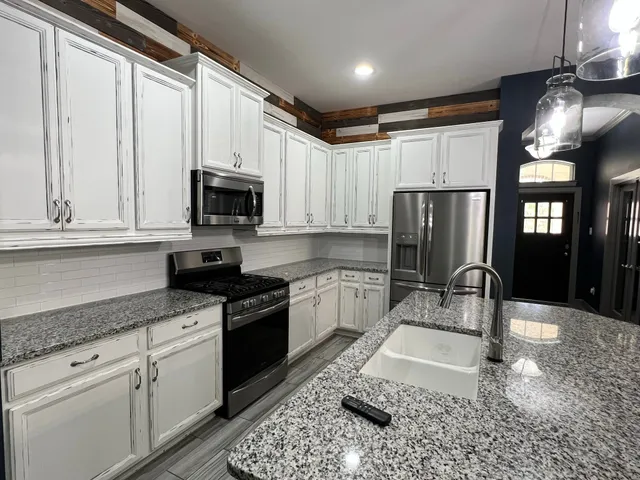 a kitchen with granite countertop a stove a sink and a microwave